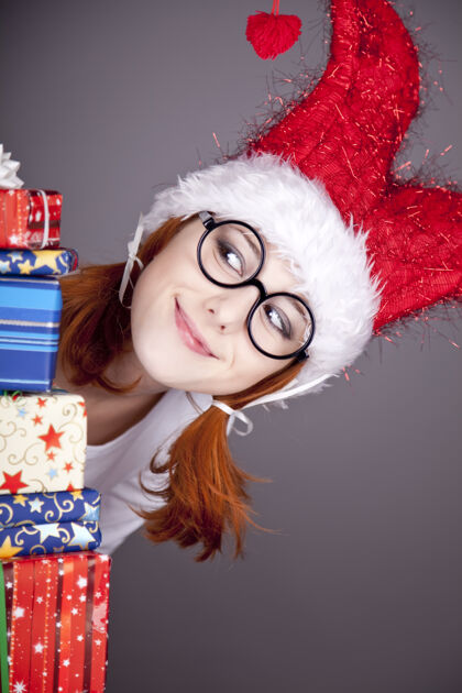 礼物滑稽的红发女孩戴着圣诞帽 手里拿着礼品盒帽子可爱服装
