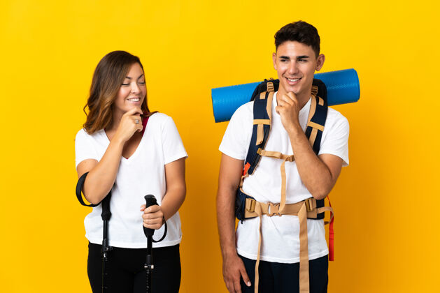 运动一对年轻的登山夫妇背着一个黄色的大背包 面带微笑地看着身边侧线冒险男性