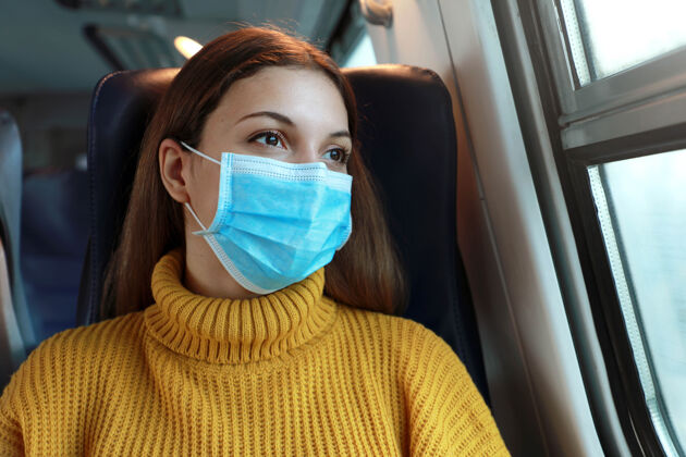 看戴着外科口罩的女性通勤者透过火车窗口的特写镜头窗快乐女孩