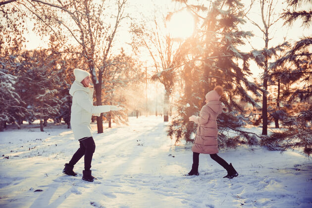 孩子妈妈和女儿在冬季公园玩得很开心童年雪女人