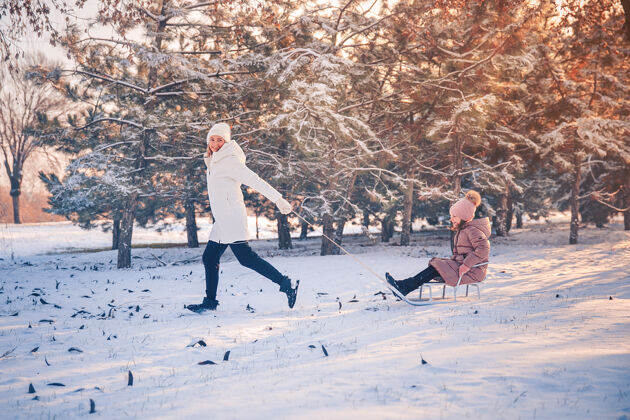 快乐妈妈和女儿在冬季公园玩得很开心妈妈年轻女儿