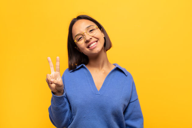 积极年轻的拉丁女人微笑着 看上去很快乐 无忧无虑 积极乐观 用一只手示意胜利或和平放松年轻休闲