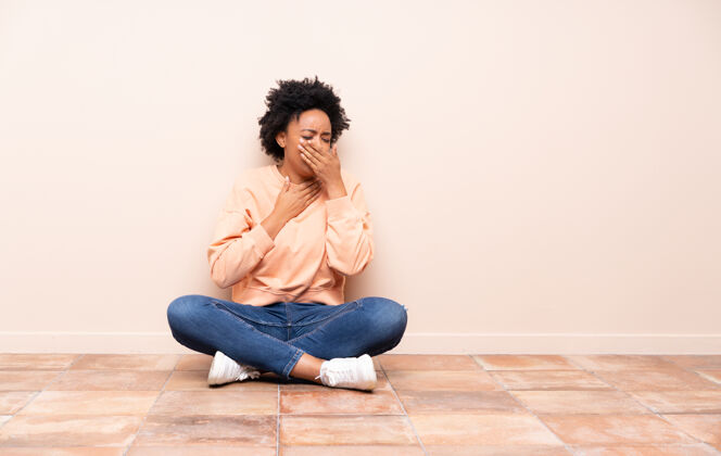 美国人坐在地板上的非洲裔美国妇女咳嗽 感觉不好非洲成人地板