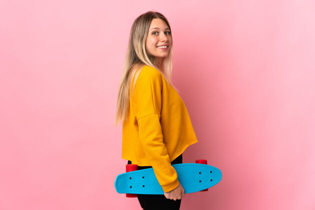 人年轻的金发女人穿着溜冰鞋被隔离在粉红色的地板上减肥游戏女性
