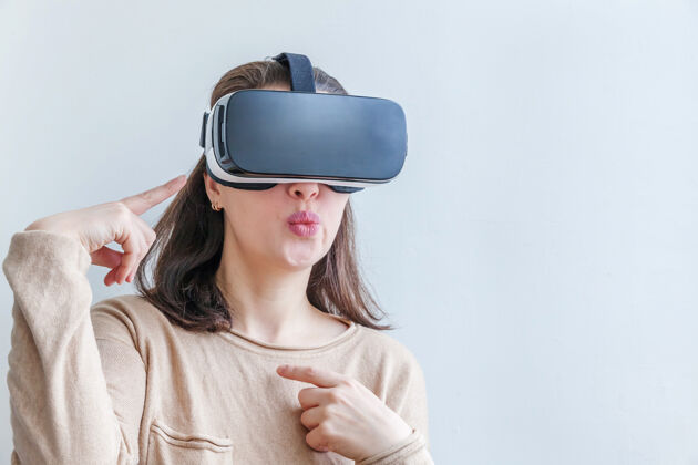 头盔微笑的年轻女子戴着虚拟现实vr眼镜头盔耳机在白色背景上高科技体验虚拟