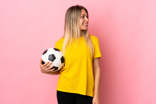 人一个年轻的足球运动员 站在粉红色的一边看着她笑比赛十字架