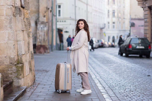 探索一个手里拿着电话和手提箱在新城市里散步的女人行政摄影景点