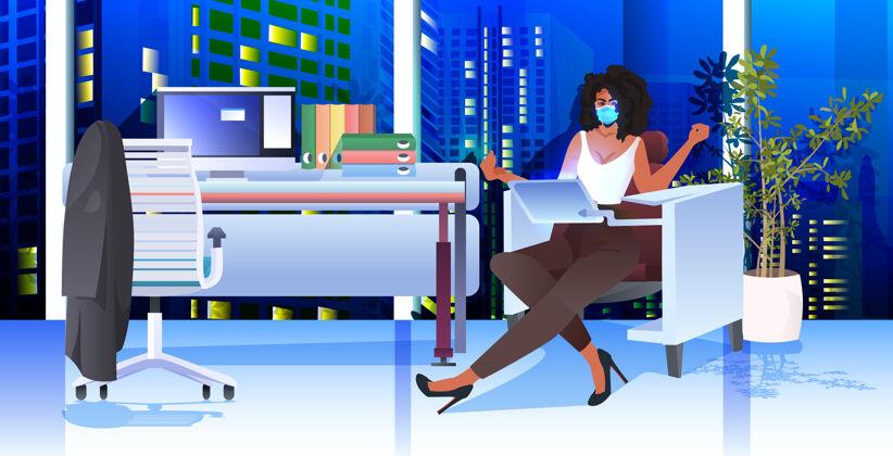 夜晚女商人戴着口罩坐在工作场所 用笔记本电脑和冠状病毒大流行概念现代办公室室内水平公司预防同事