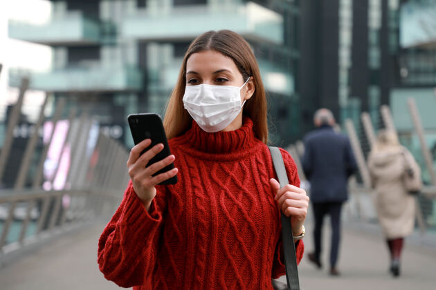 技术戴着口罩走在城市街道上的年轻女商人户外保护电话