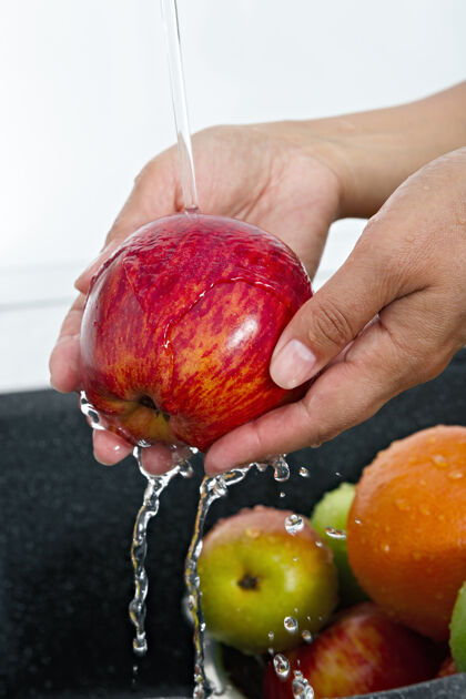 飞溅女厨师在自来水龙头下洗苹果营养水果水龙头
