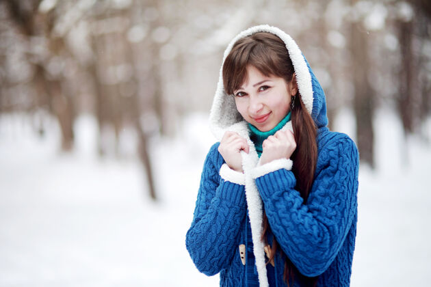 积极雪林中一个穿着蓝色毛衣的可爱女孩的冬季肖像女孩人毛衣