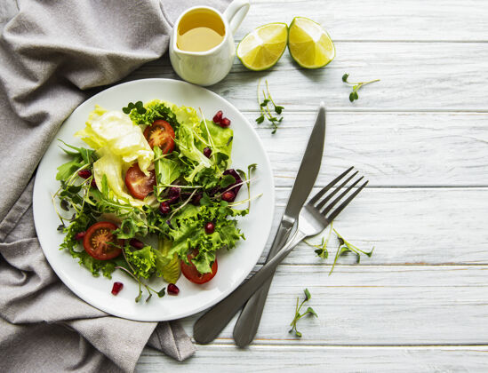 萝卜新鲜的绿色混合沙拉碗 白色木质表面上有西红柿和小绿叶健康食品素食主义者顶视图