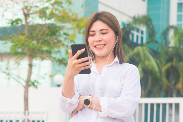 商店亚洲女人用智能手机听音乐观看亚洲女人肖像