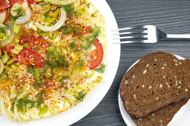 一餐在木桌上的白色盘子里放着香草和蔬菜的煎蛋卷乡村开胃菜食用