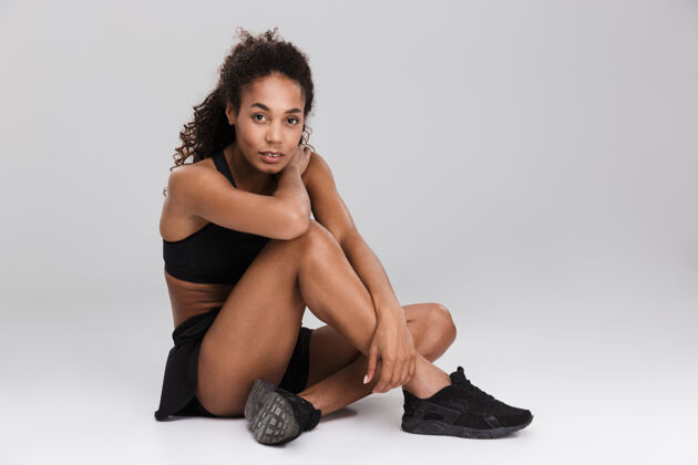 身体一位年轻漂亮的非洲女运动员在灰色墙壁上训练后放松的画像美国人放松活力