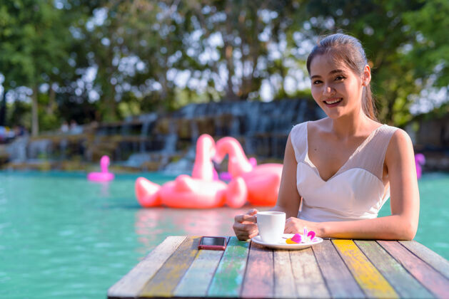 年轻美丽的亚洲女游客在湖边户外放松的画像微笑公园年轻