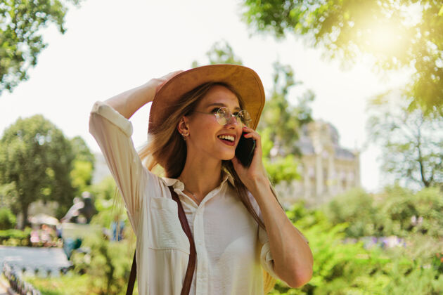 快乐一个年轻的一心一意的金发女人在电话里说话 在城市户外散步的肖像情感散步女人