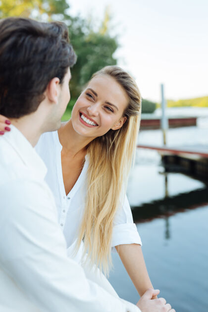 情感幸福的关系快乐的年轻女子微笑着对她的丈夫 而坐在一起与他在河边深情关系消遣