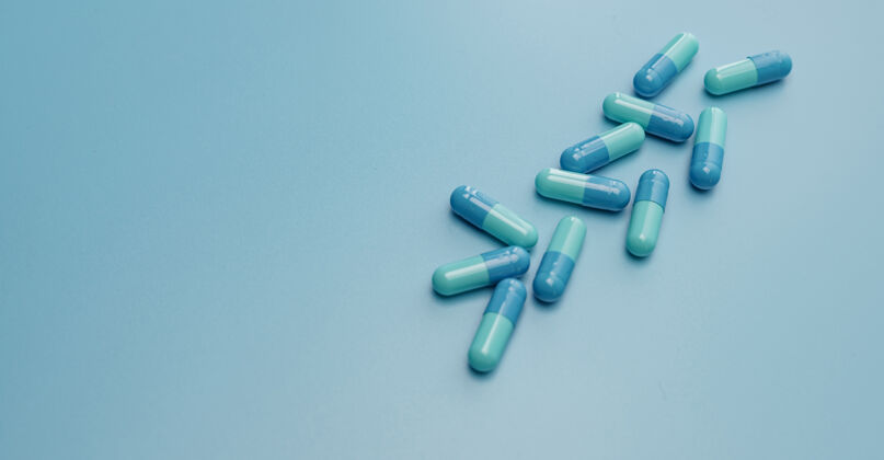 保健蓝色的胶囊在蓝色的表面上药丸止痛药医疗