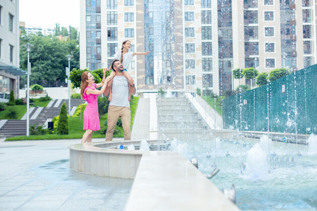 积极愉快的时光愉快的一家人在看喷泉的同时在附近散步教养住宅乐观