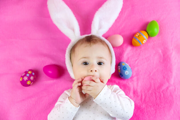 抱着穿得像兔子的宝宝 带着复活节彩蛋过复活节可爱有趣幼儿