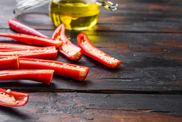 切片成熟的辣椒片 用来做辛辣的橄榄油 放在旧的深色木桌上辛辣油无花果香料
