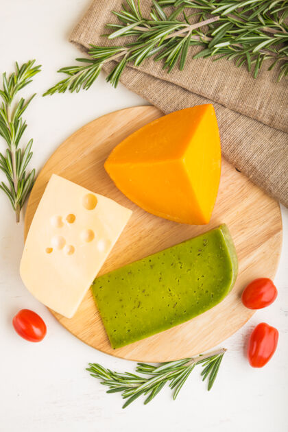 俯视图绿色罗勒奶酪和各种奶酪与迷迭香和西红柿在木板上的白色木质表面各种草药木材