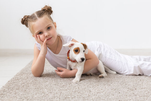 小狗童年 宠物和狗的概念-小女孩和小狗在地板上摆姿势血统品种人类