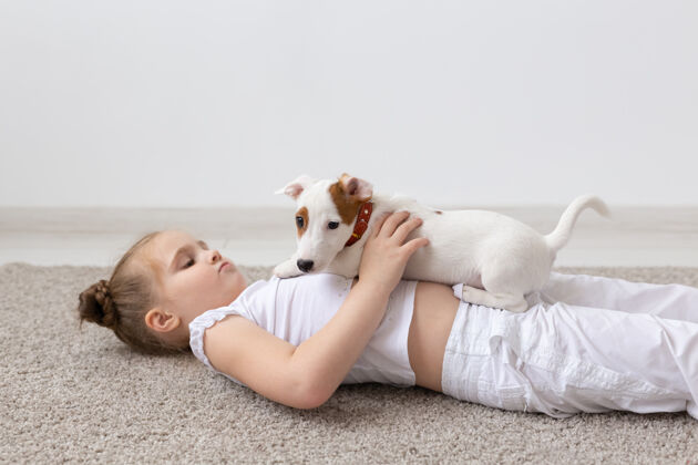 空气小女孩躺在地板上 手里拿着可爱的小狗毛皮狗高加索