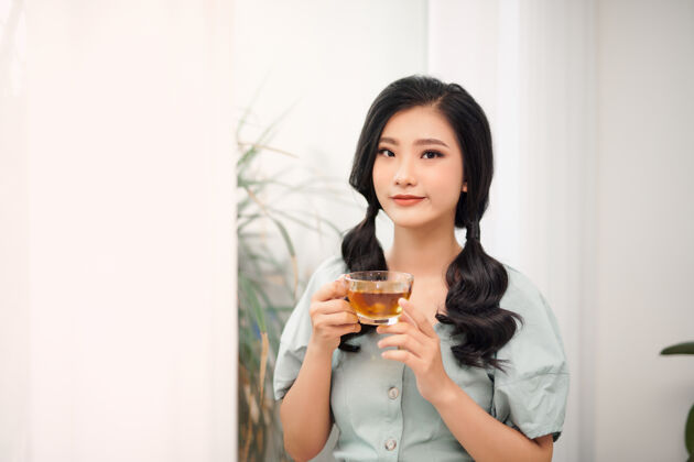 可爱的年轻迷人的亚洲女人谁喝茶微笑休息休息