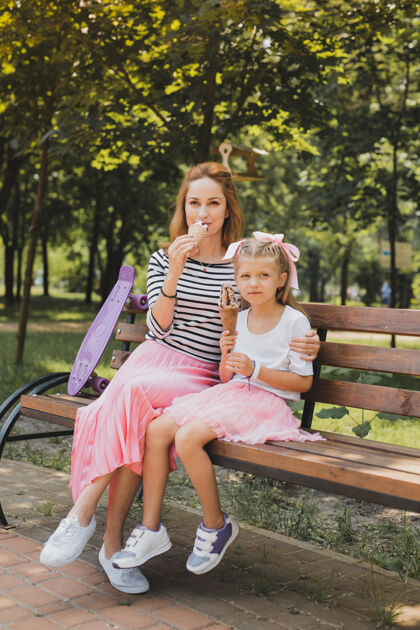 父母时尚的运动鞋时尚的母亲和女儿穿着时尚的运动鞋坐在公园的长凳上坐着顶视图感情
