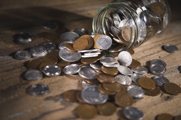 改变硬币是从一个玻璃瓶里洒在木桌上的投资联合利润
