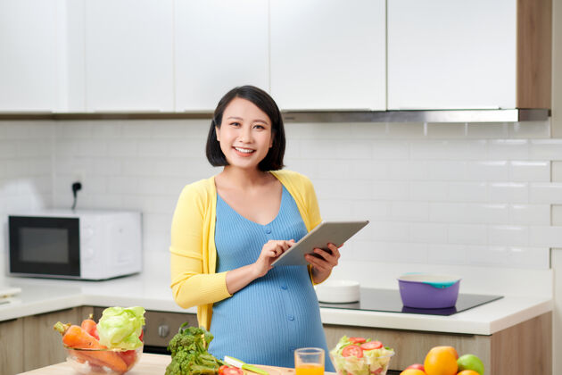饮食孕妇在室内准备健康膳食 通过便携式电脑搜索素食食谱早餐食谱肚子