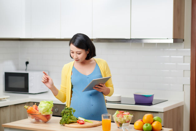 食谱孕妇在室内准备健康膳食 通过便携式电脑搜索素食食谱产妇电脑营养
