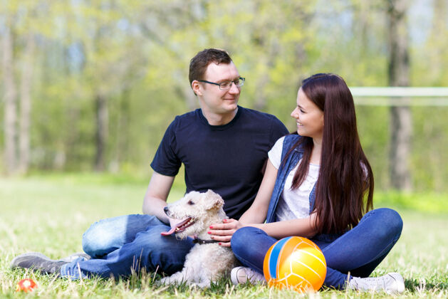 关系快乐的家庭和他们的狗在公园里女孩乐趣爱