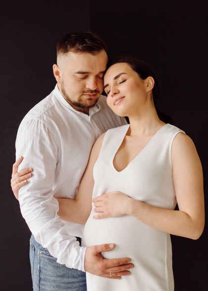 腹部快乐迷人的孕妇和她的丈夫在摄影棚里合影腹部爱女人