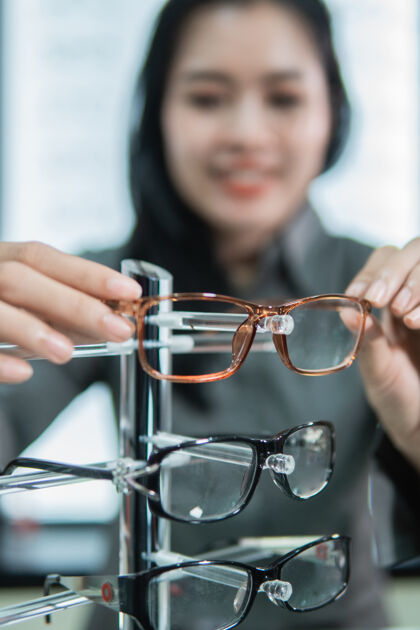 焦点一位女顾客在眼镜店试用后 把眼镜架放在架子上的选择性聚焦眼镜货架尝试