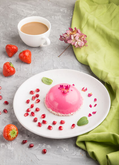 食物粉色的草莓慕斯蛋糕和一杯咖啡放在灰色的水泥表面和绿色的纺织品上草莓混凝土早餐