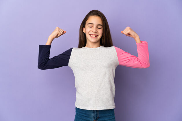 强壮小女孩孤零零地站在紫色的墙上做着坚强的手势满足有趣女孩