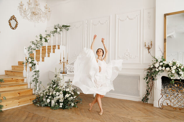 人穿着白色裙子的芭蕾舞演员在经典的老式大厅里芭蕾女性姿势