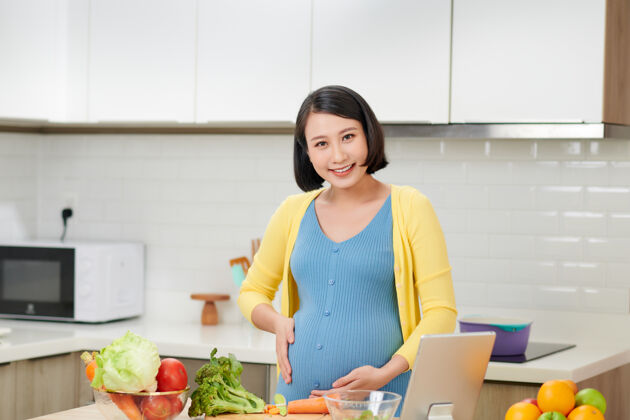 女孩年轻的孕妇在家厨房准备健康的食物和大量的蔬菜饮食中国女人