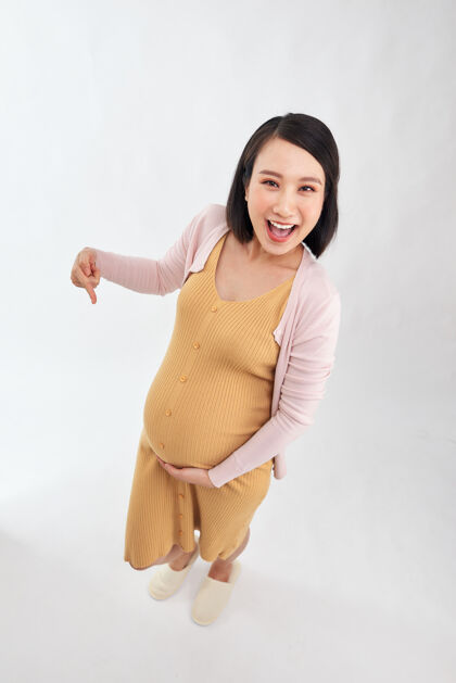 护理亚洲孕妇幸福地用手指在肚子上指指点点就白了中国人家庭期望