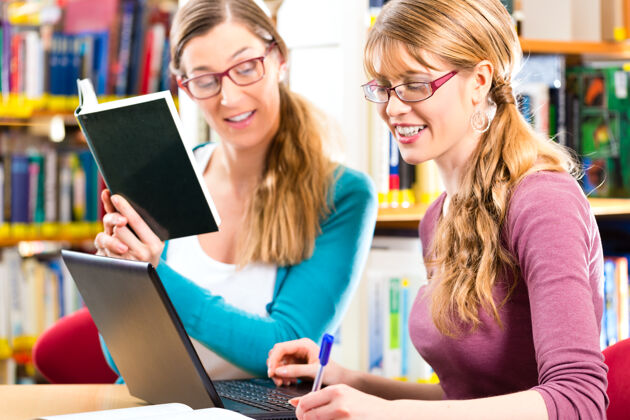 电子书学生-年轻女性在图书馆与笔记本电脑和书籍学习小组高加索学生女性
