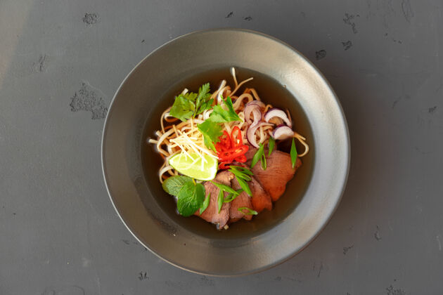料理亚洲汤拉面配猪肉和面条在灰色的表面顶视图蛋拉面