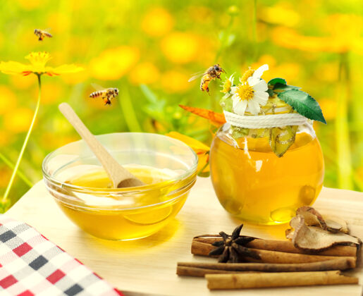 罐子蜂蜜在玻璃罐里 蜜蜂在飞 花在木地板上健康玻璃流