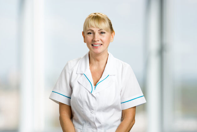 微笑友好的女医生的肖像微笑的成熟护士或医生站着欢乐保健工作