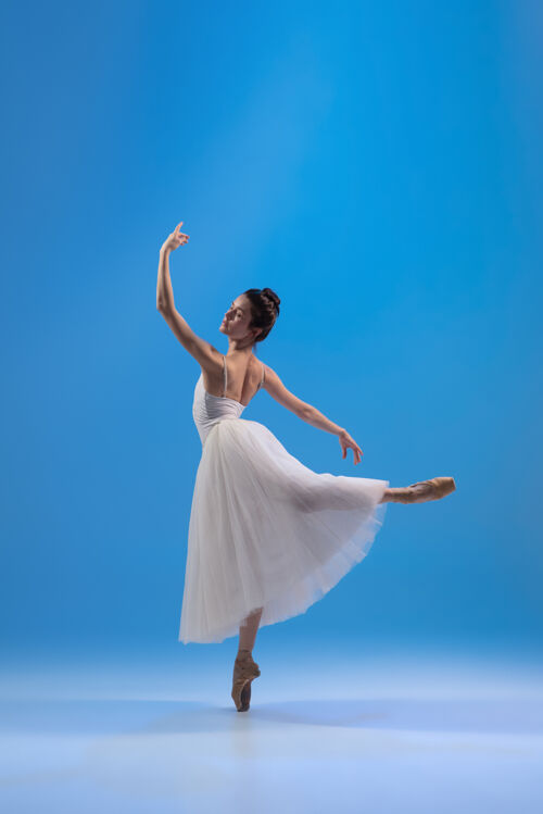 美丽年轻优雅的白裙芭蕾舞演员 孤零零地站在蓝色的墙上肖像辉光年轻
