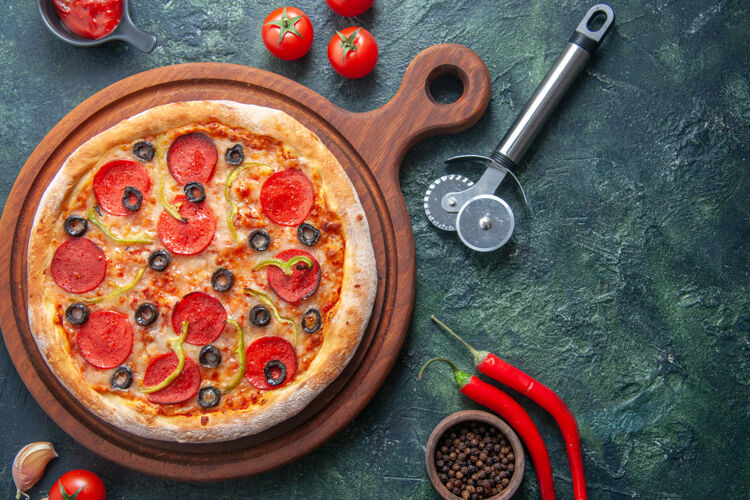 晚餐美味的自制比萨饼放在木制砧板上 番茄蒜番茄酱辣椒放在孤立的黑暗表面上番茄酱午餐美味
