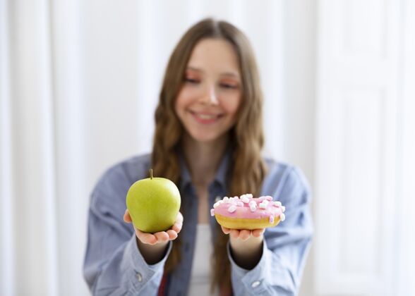 健康中等身材的女人 带着甜甜圈和苹果食物保健生活方式