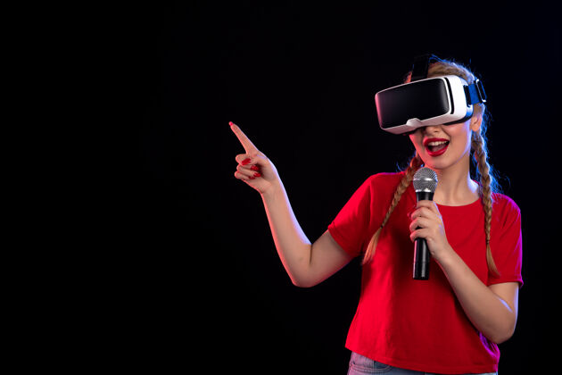 音乐家在黑暗的视觉游戏音乐中 年轻女性玩虚拟现实和用麦克风唱歌的肖像表演麦克风游戏